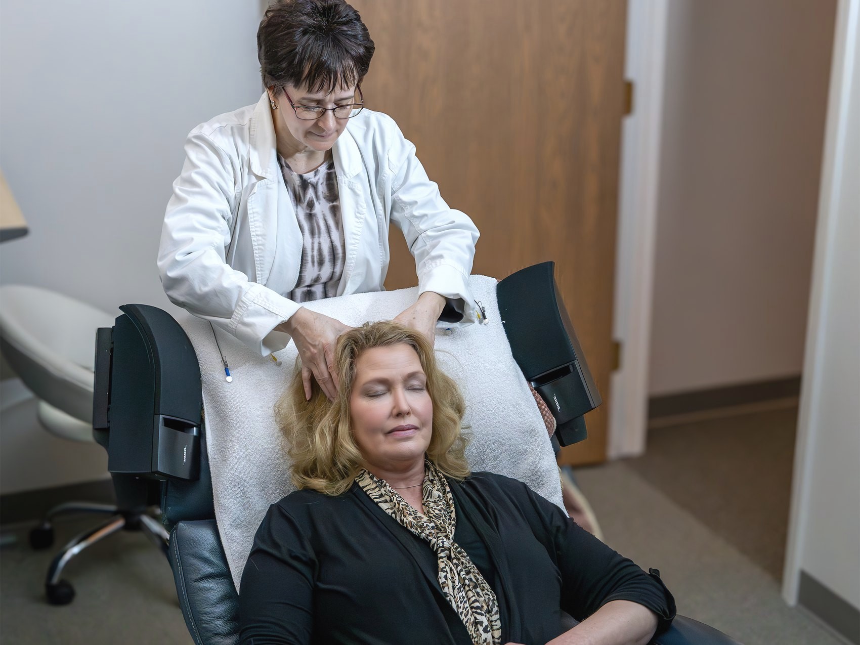 A Brain Life Center technologist placing read-only neurofeedback sensors as a client reclines with her eyes closed